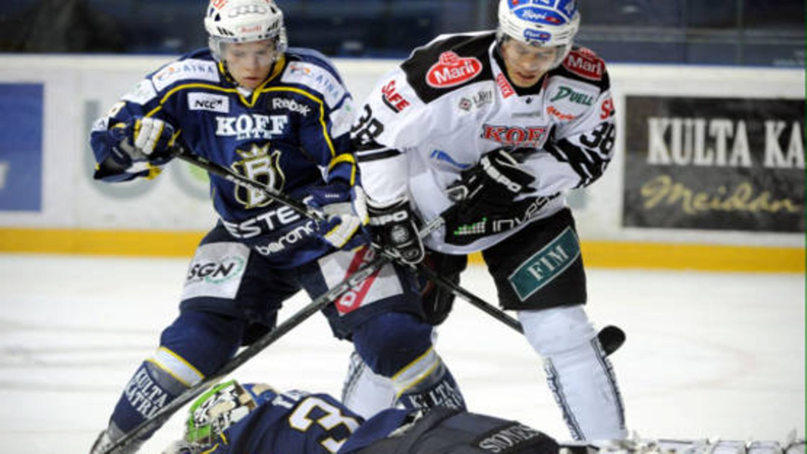Bluesin Ville Varakas ja TPS:n Sami Venäläinen maalivahti Iiro Tarkin takana jääkiekon SM-liigan ottelussa Espoon Blues vs TPS, Espoossa 7. joulukuuta 2010.