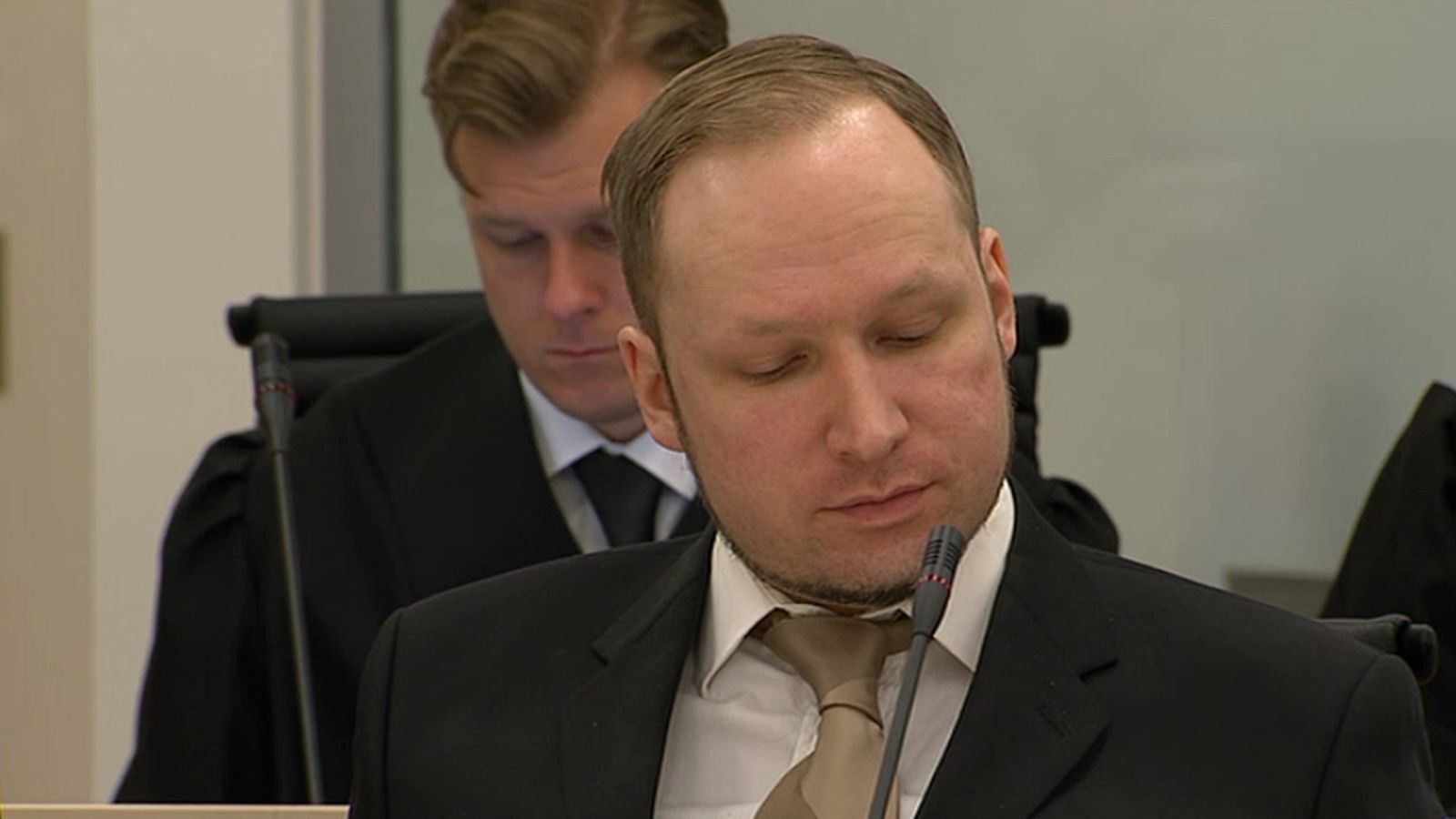 Breivik kuuntelee syytteiden lukua tyynesti.