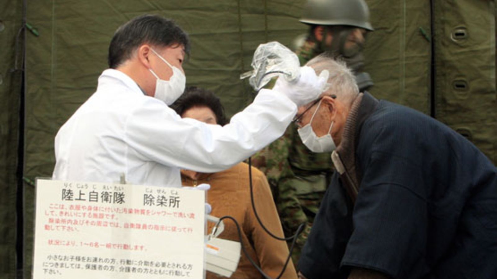 Japanin asevoimien lääkärit tarkastavat paikallisia asukkaita säteilyn varalta Otaman kylässä Fukushiman prefektuurissa 13.3.2011.
