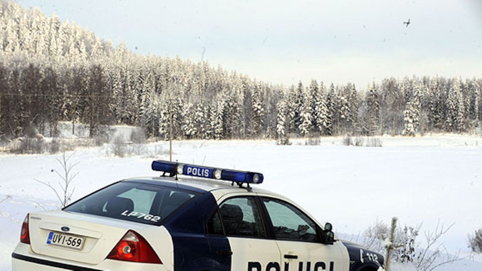 Poliisit vartioimassa Hornetin putoamispaikkaa Juupajoen Kopsamon kylässä torstaina 21.tammikuuta 2010. Putoamispaikan yllä Ilmavoimien lentokone. (LEHTIKUVA)