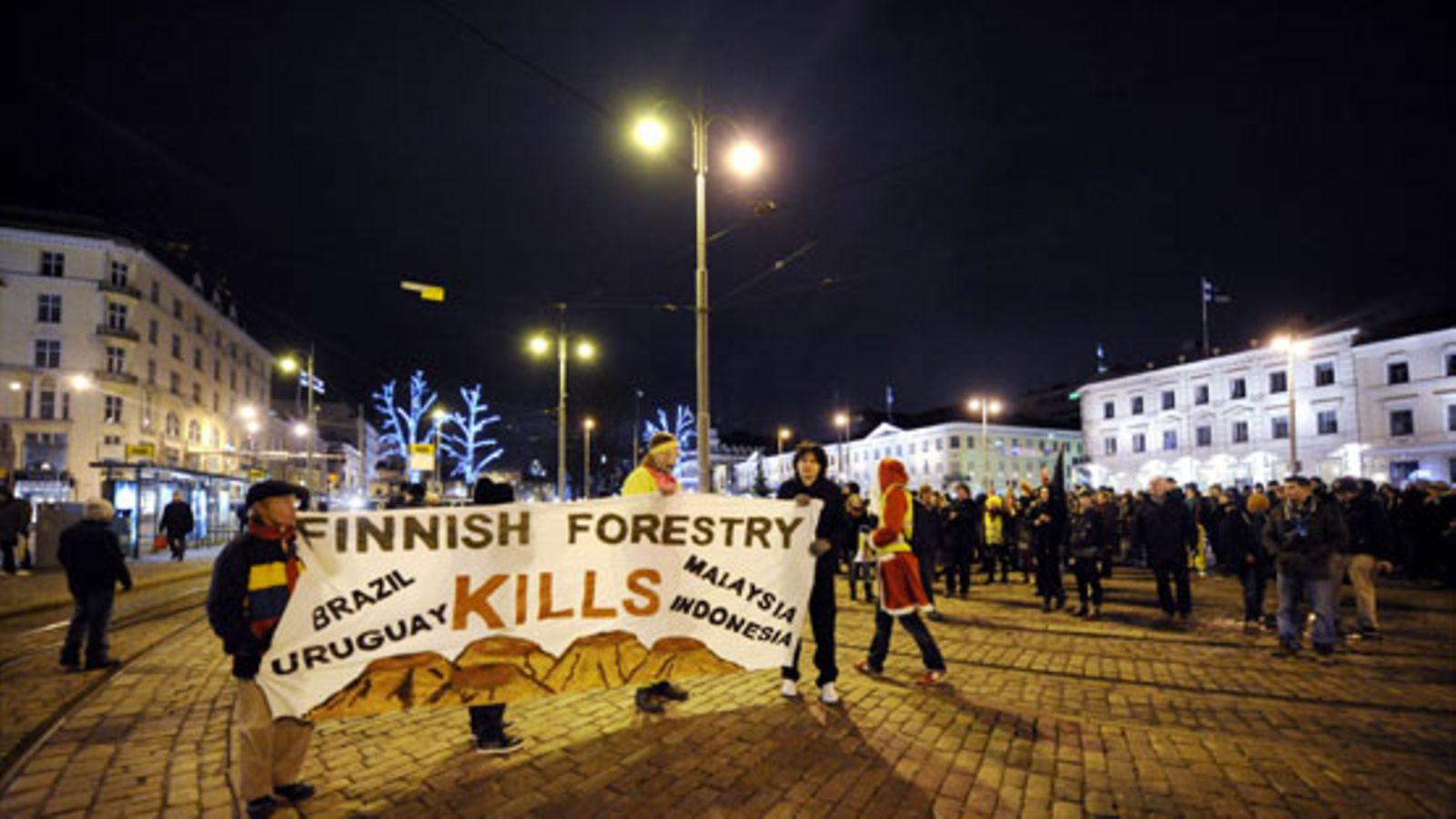 Kuumotuskulkueen" mielenosoittaja polttaa Suomen lippua itsenäisyyspäivänä Kauppatorilla Helsingissä 6. marraskuuta 2009. Mielenosoitus oli suunnattu mm. Suomen ilmasto- ja ympäristöpolitiikkaa sekä metsäteollisuutta vastaan.