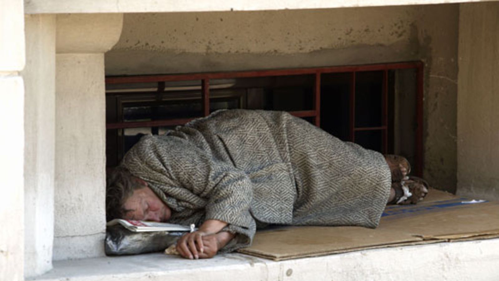 Koditon nukkuu rakennuksen ikkunasyvennyksessä. / A homeless woman sleeps in the streets of Bucharest, Romania.