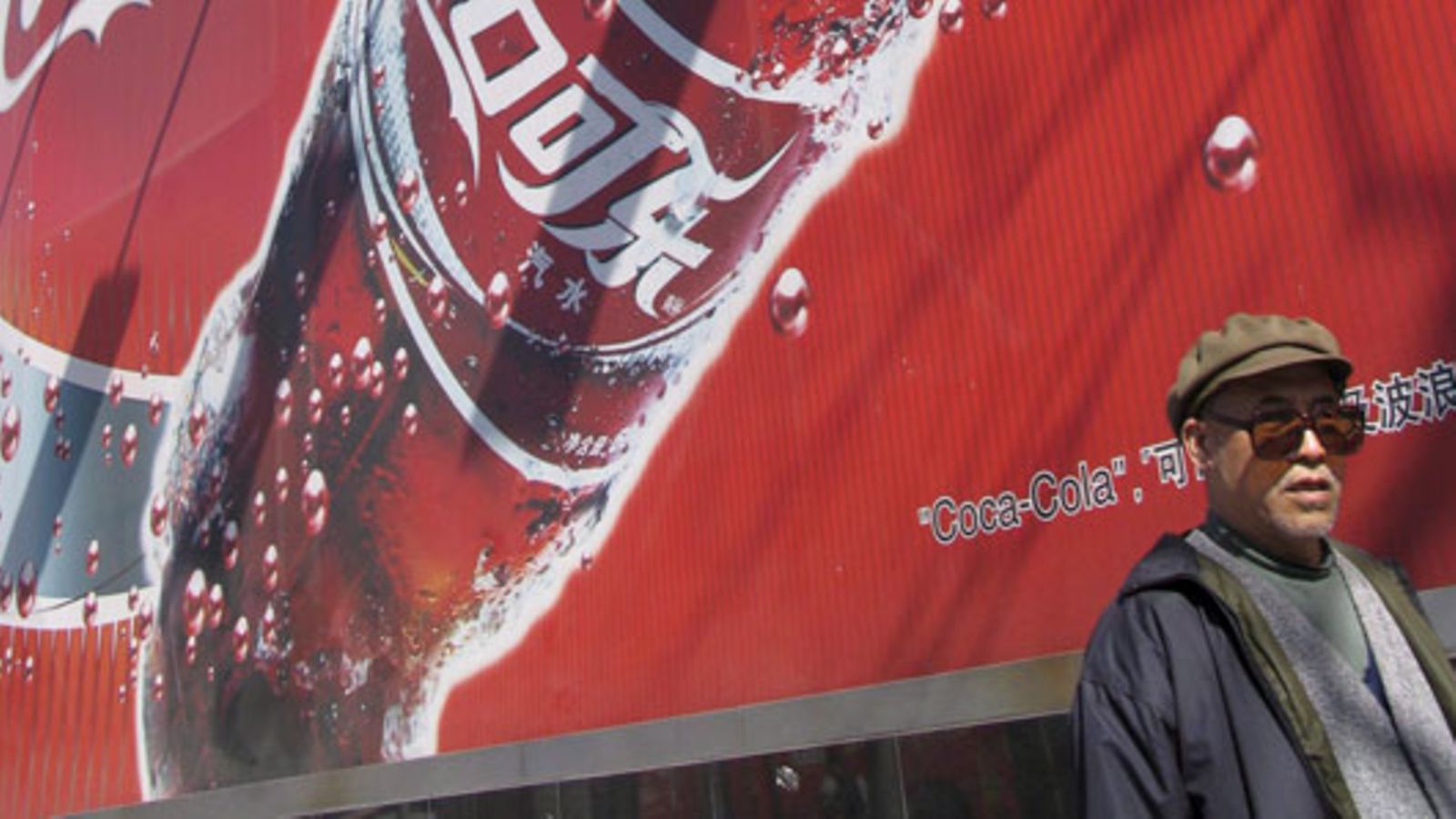 Ohikulkija Coca Cola -mainoksen edessä Pekingissä. Kuva: EPA