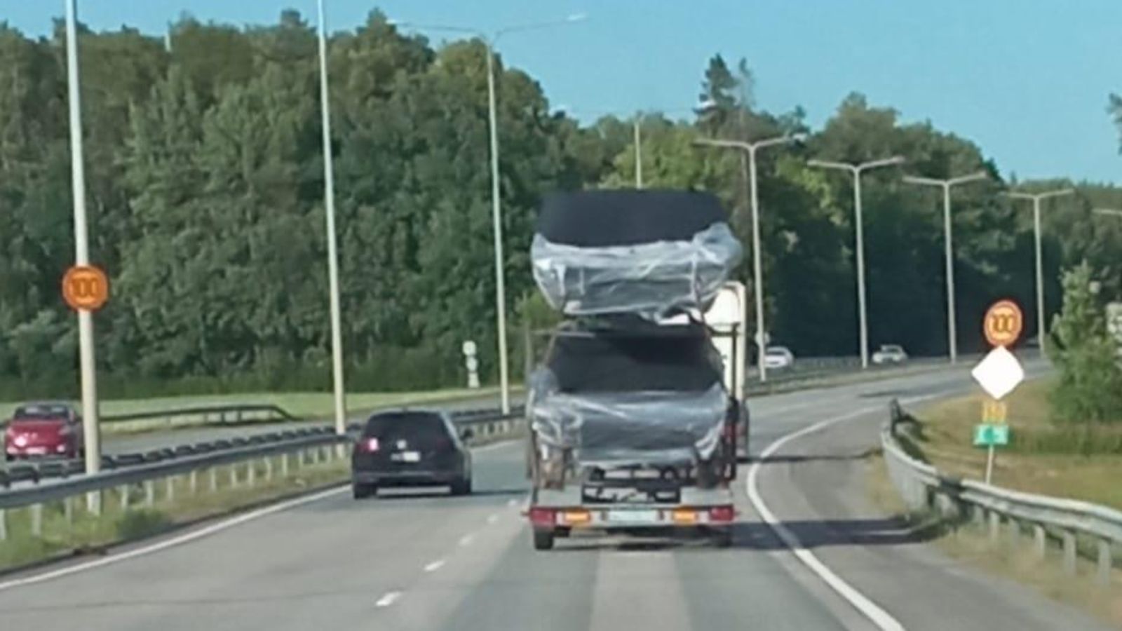 Kaksi venettä lastattuna päällekäin trailerille pienen auton vetämänä.