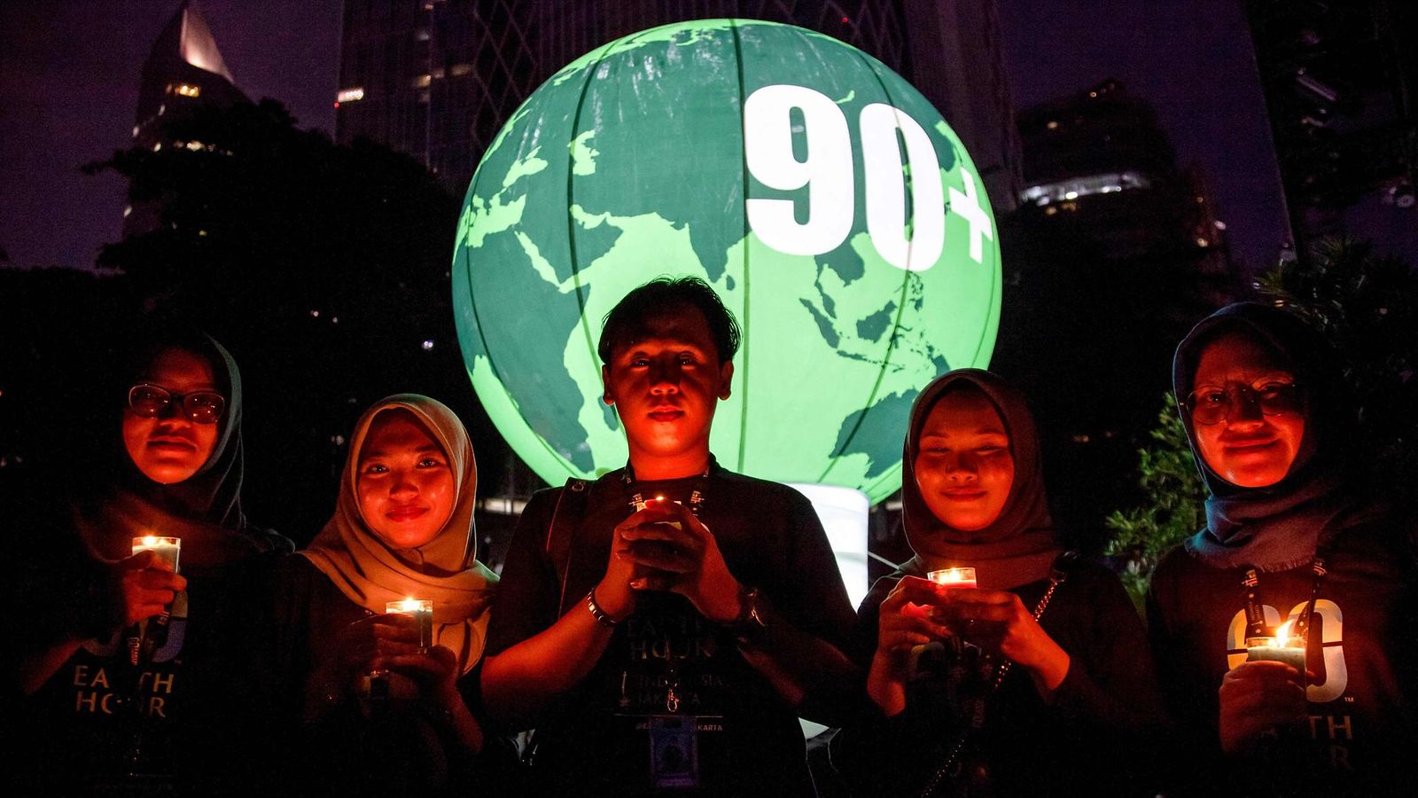 LK 22.3.2025 Aktivistit pitävät kynttilöitä Earth Hour -ympäristökampanjan yhteydessä, jonka teemana on ”Give an Hour for Earth” Jakartassa 22. maaliskuuta 2025.