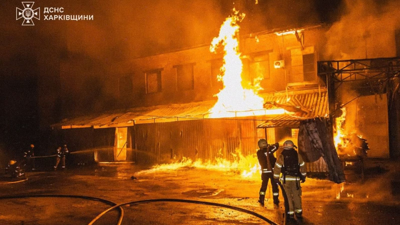 Palomiehet sammuttavat suurta rakennuspaloa yön pimeydessä.