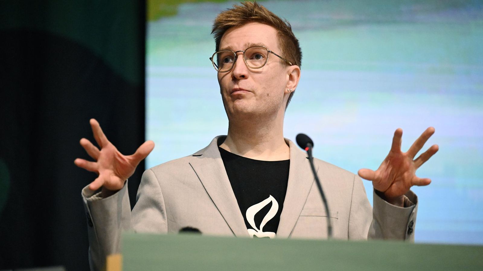 Oras Tynkkynen puhuu mikrofoniin elehtien käsillään.