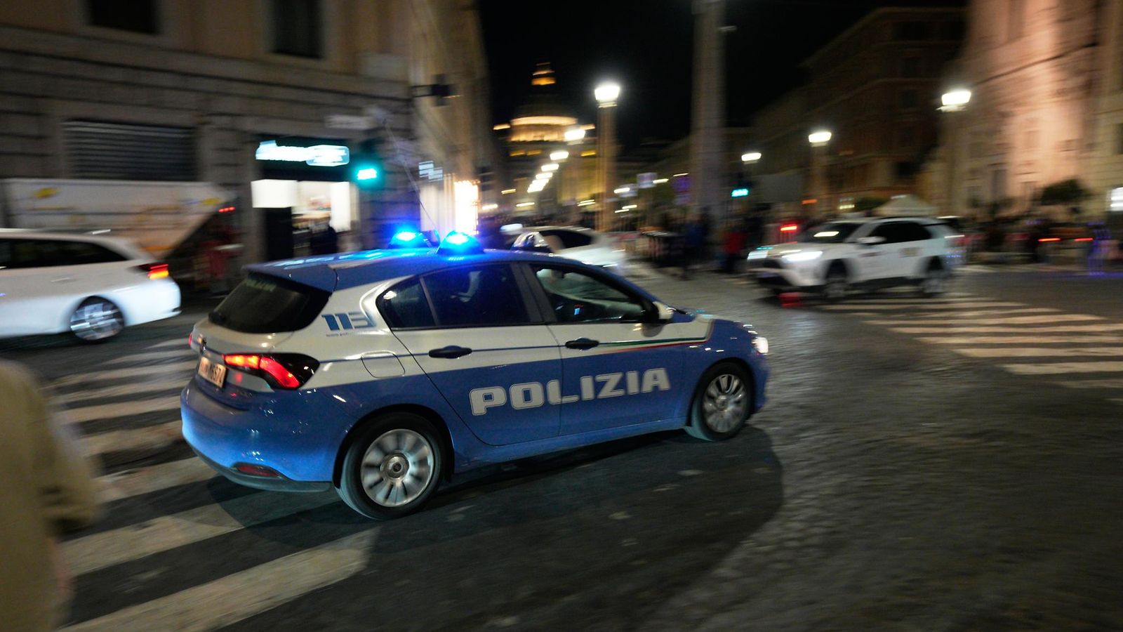 Poliisiauto kiihdyttää sireenit vilkkuen Rooman öisillä kaduilla.