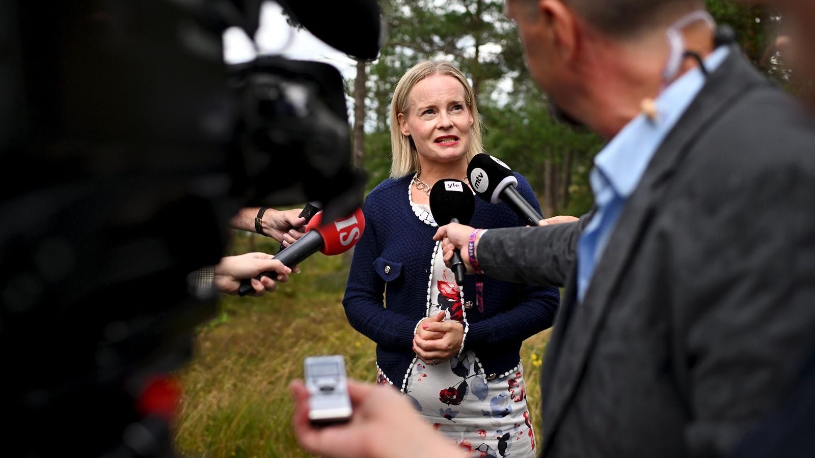 Riikka Purra puhuu toimittajalauman keskellä mikrofonien osoittaessa häntä kohti.