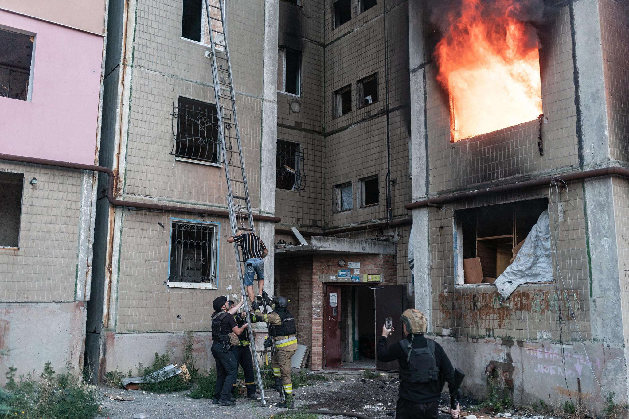 Ukrainalaiset palomiehet pelastivat miehen kotonaan sen jälkeen, kun venäläisten pommitus sytytti asuinrakennuksen tuleen Kostiantynivkassa Ukrainassa 22. elokuuta 2025.